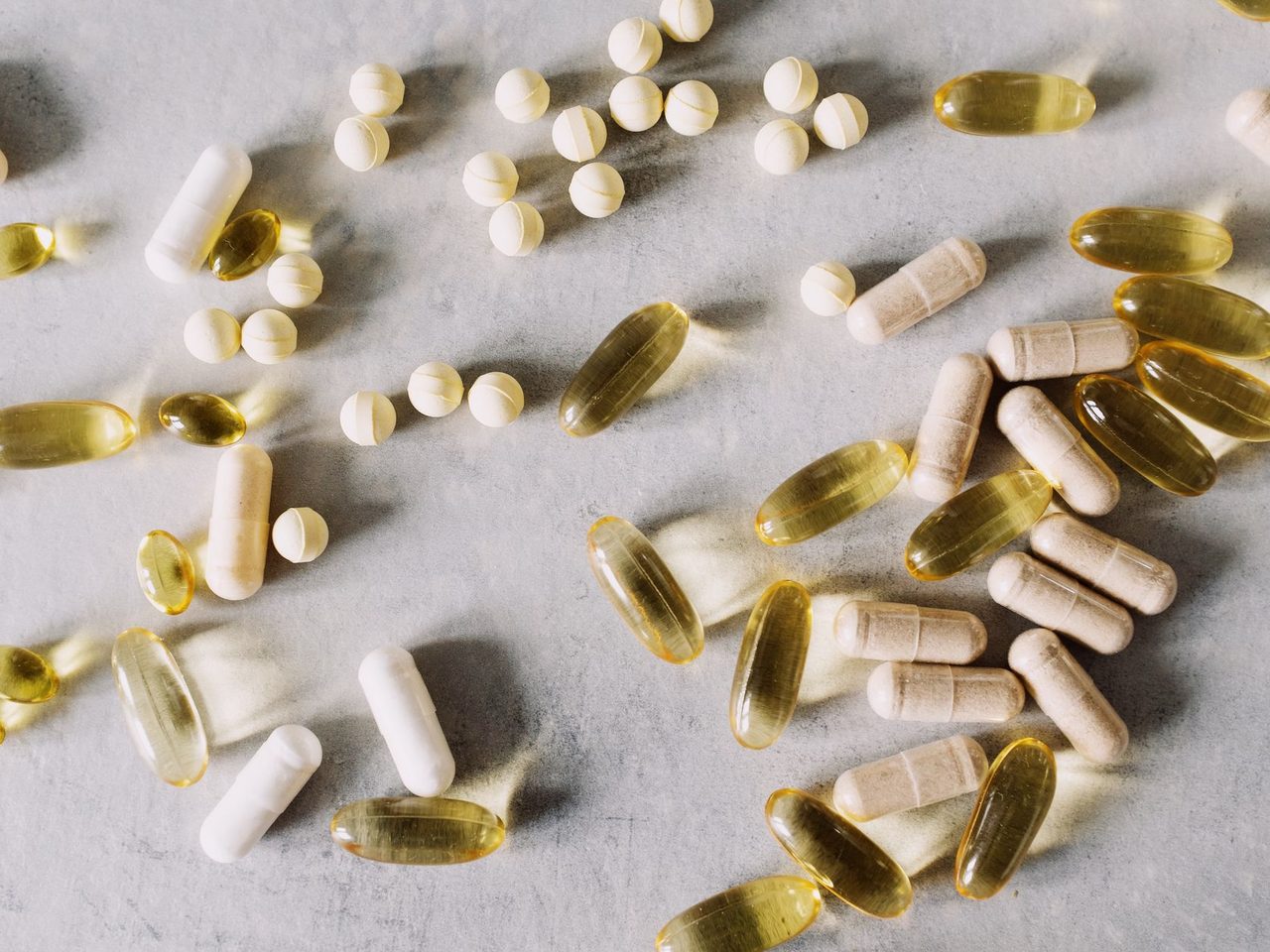 Assorted vitamin capsules and tablets scattered on a marble surface