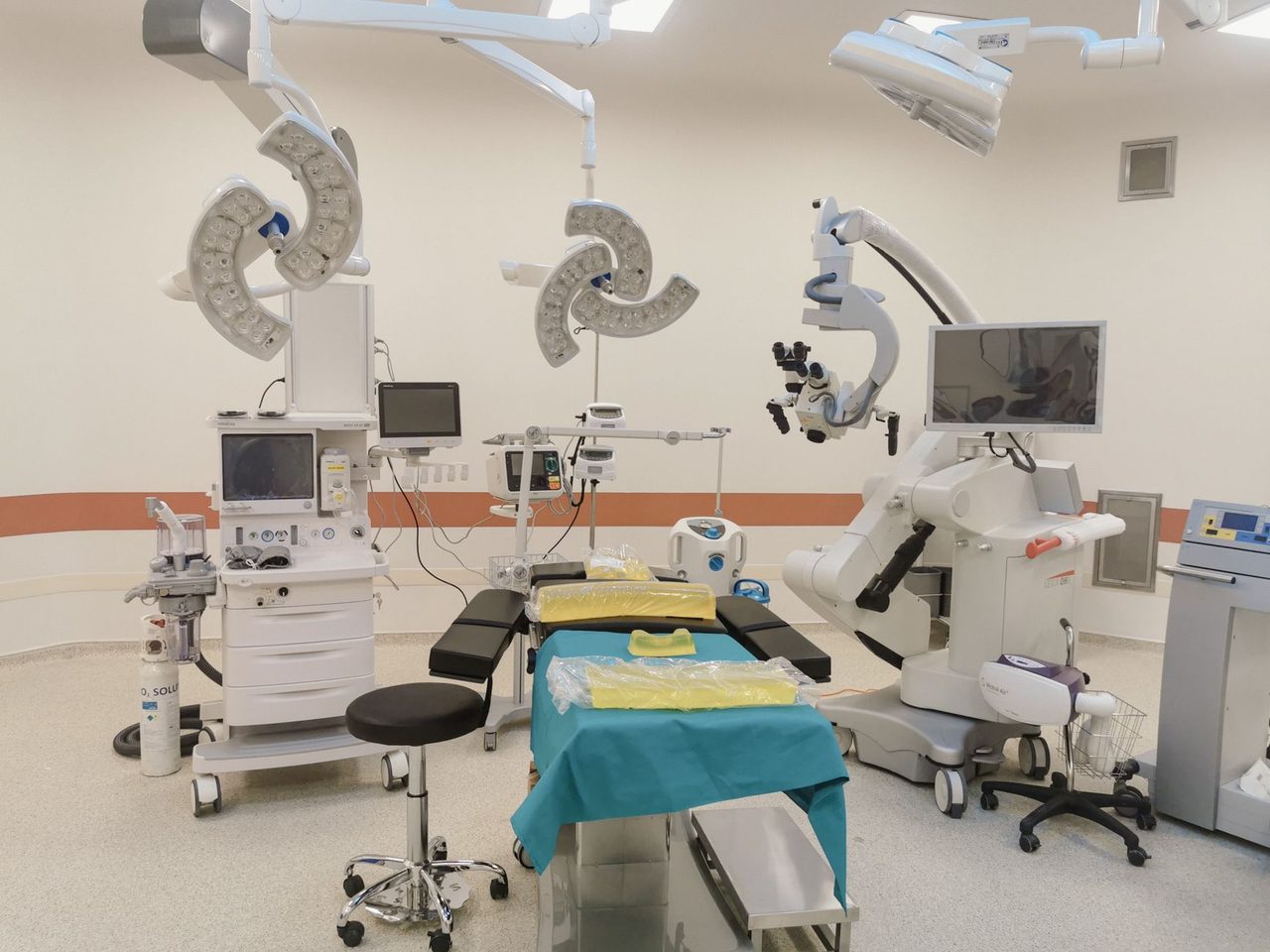 A brightly lit, empty operating room with surgical lights and equipment