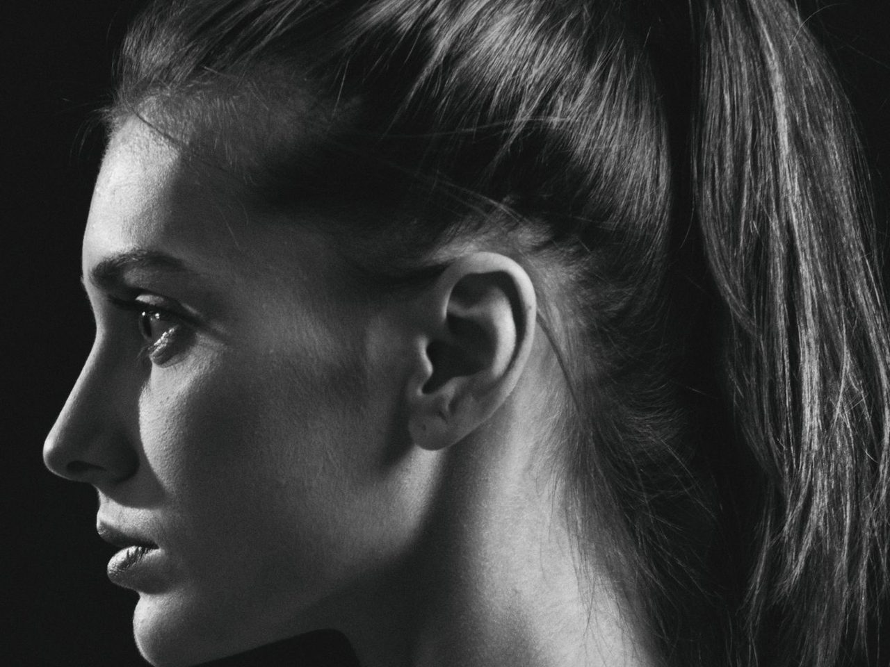 Black and white profile of a woman with her hair pulled back tightly into a ponytail