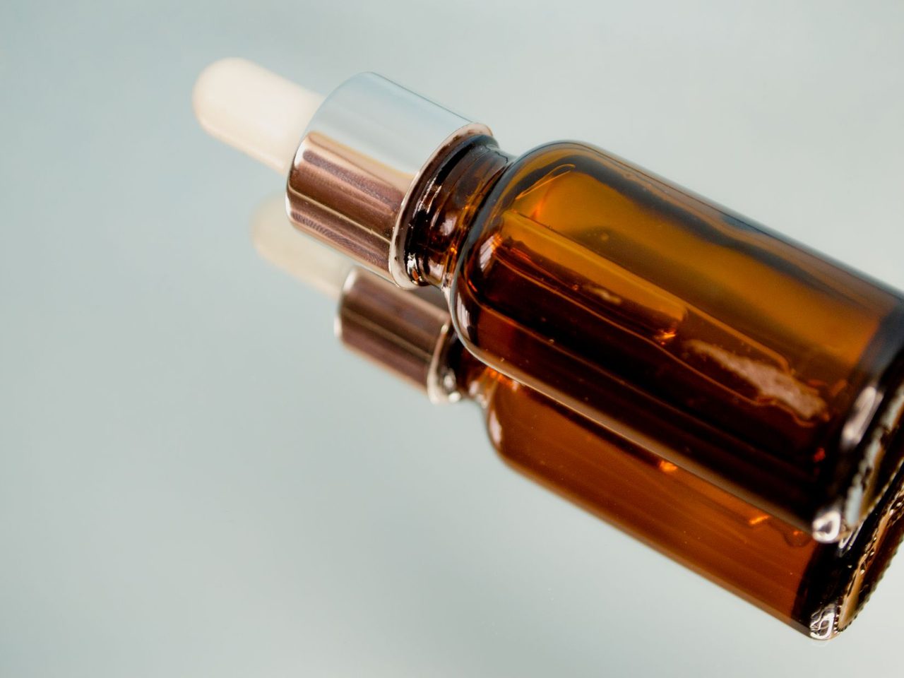 A brown glass dropper bottle lying on a reflective surface