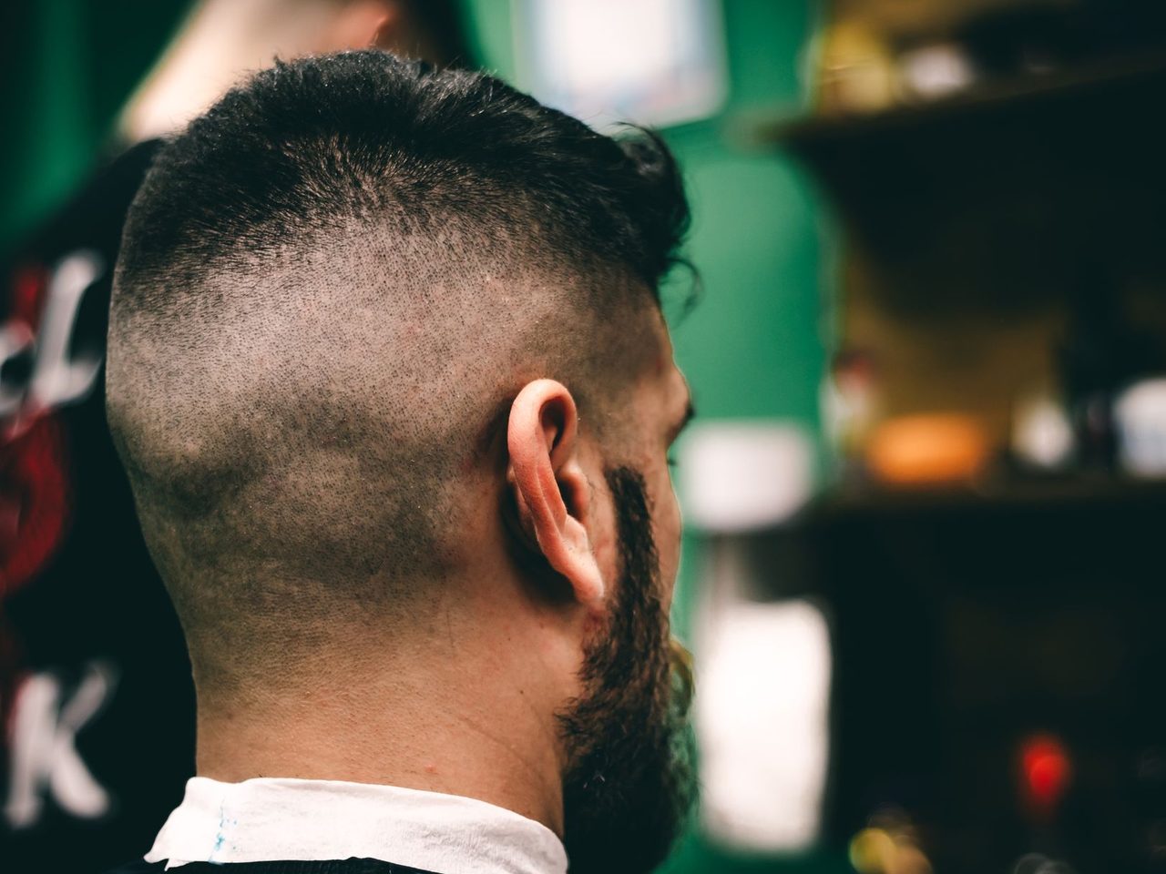 Rear view of a young man with a fresh fade haircut and a beard in a barbershop