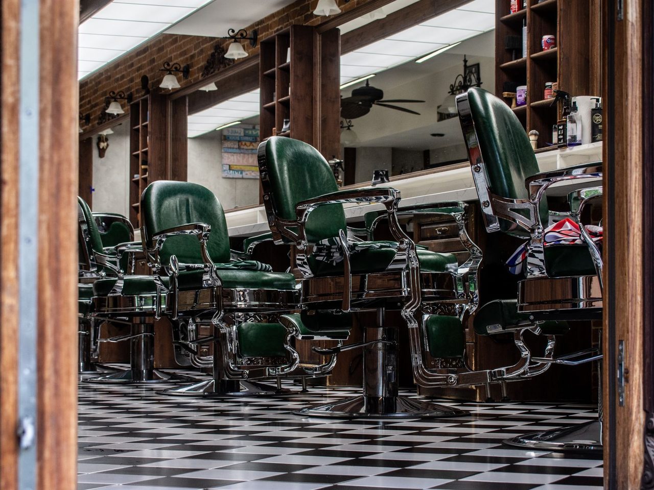 Interior of a vintage barbershop with green leather chairs and a checkered floor