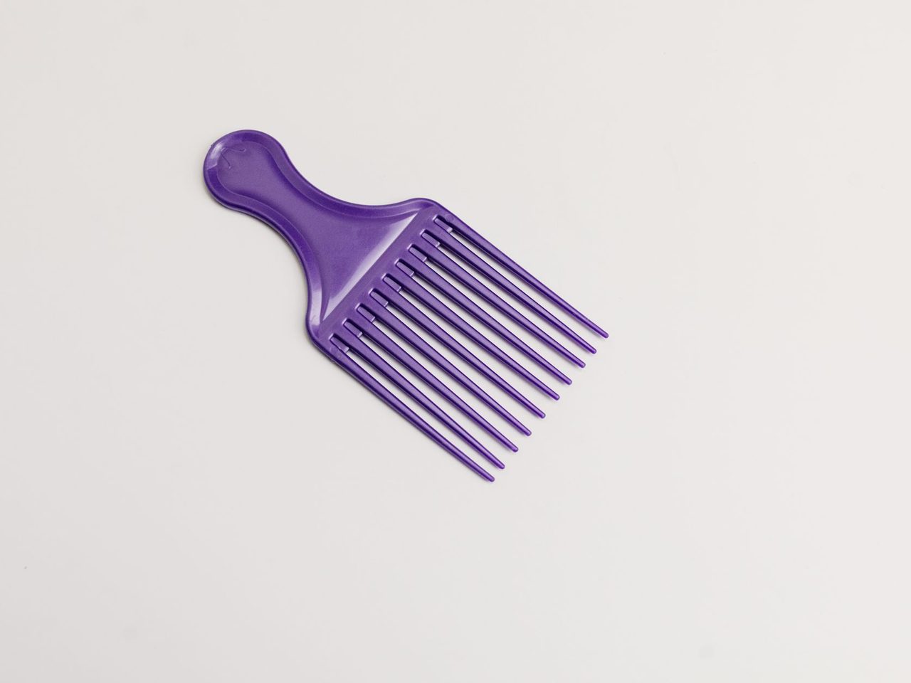 A purple wide-tooth hair pick comb on a plain white background